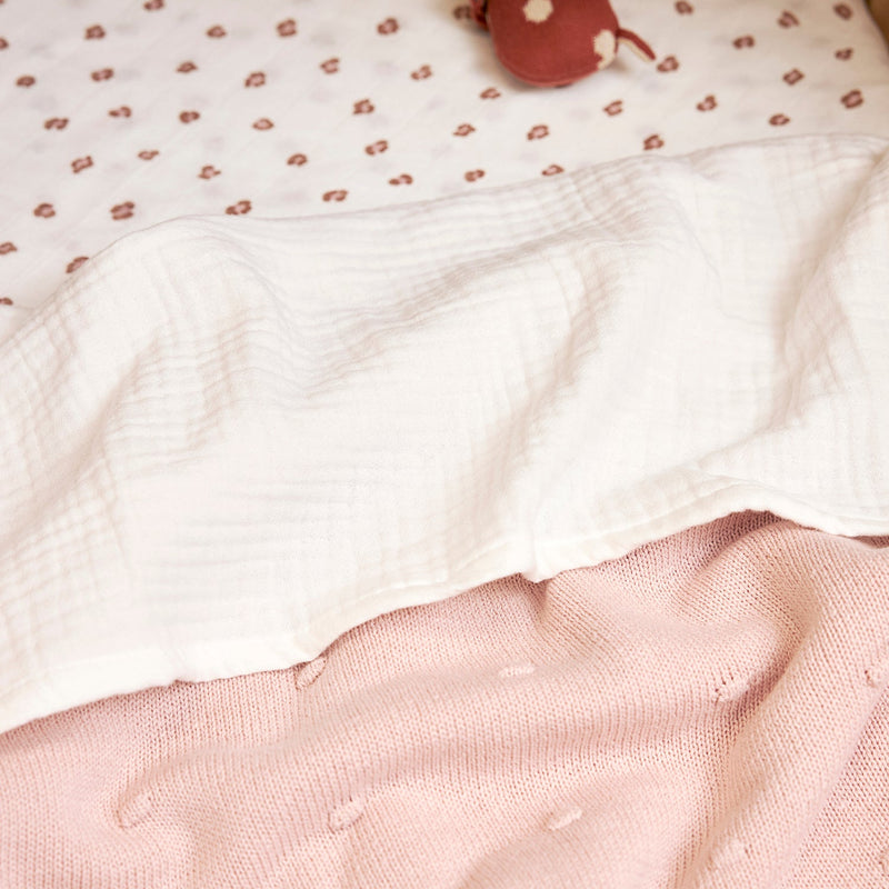Meyco Offwhite muslin sheet folded over a knitted blanket