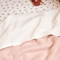 Meyco Offwhite muslin sheet folded over a knitted blanket