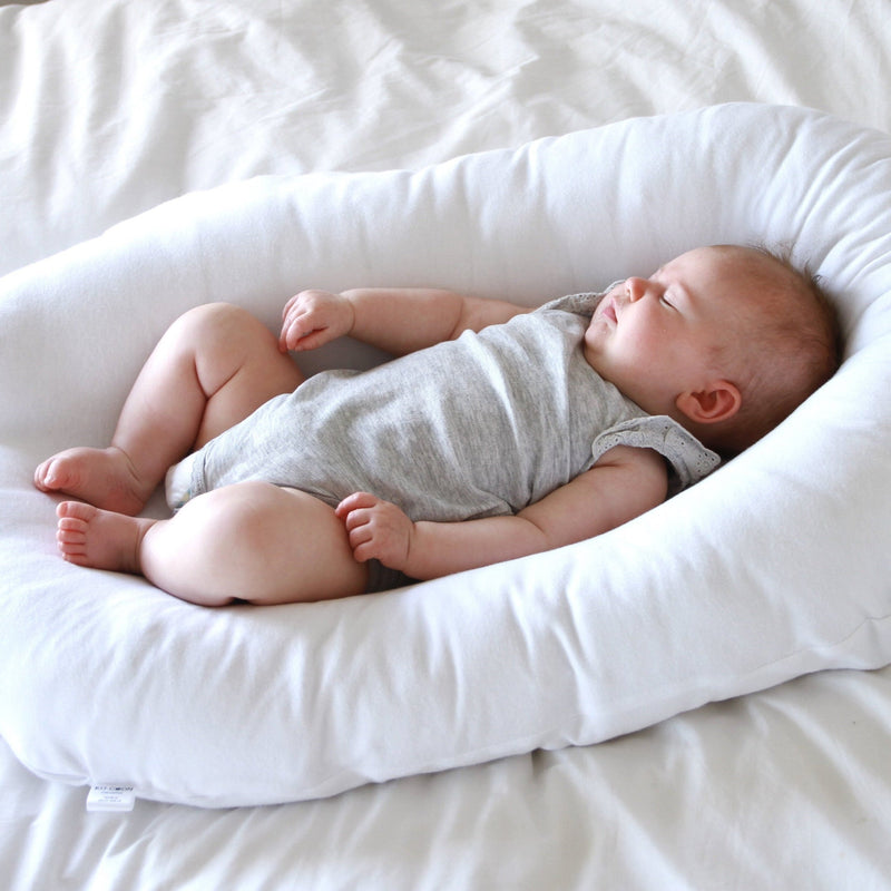 Baby in the Ko-Coon nesting pod on a bed